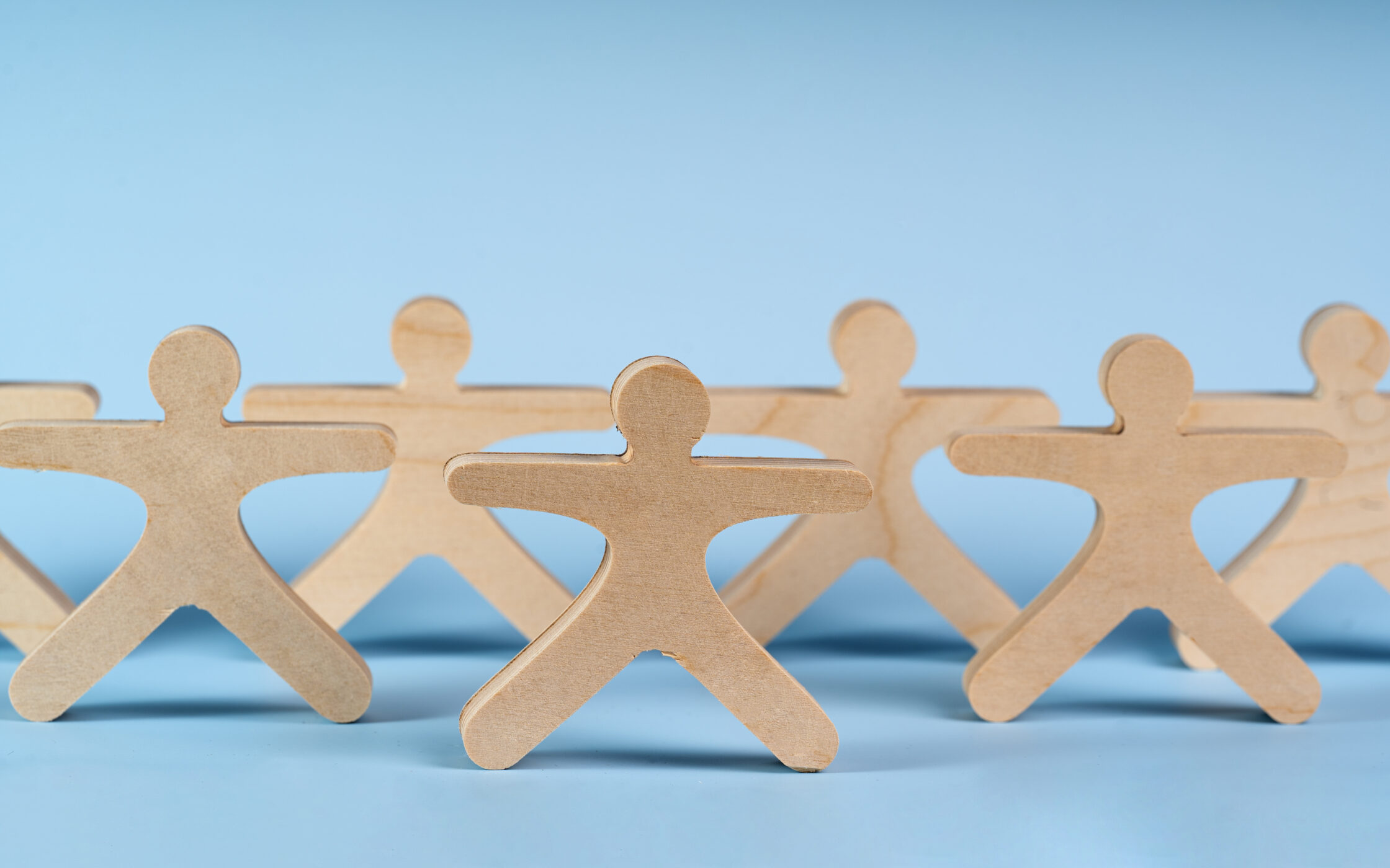 Wooden figure people holding hands and building a community