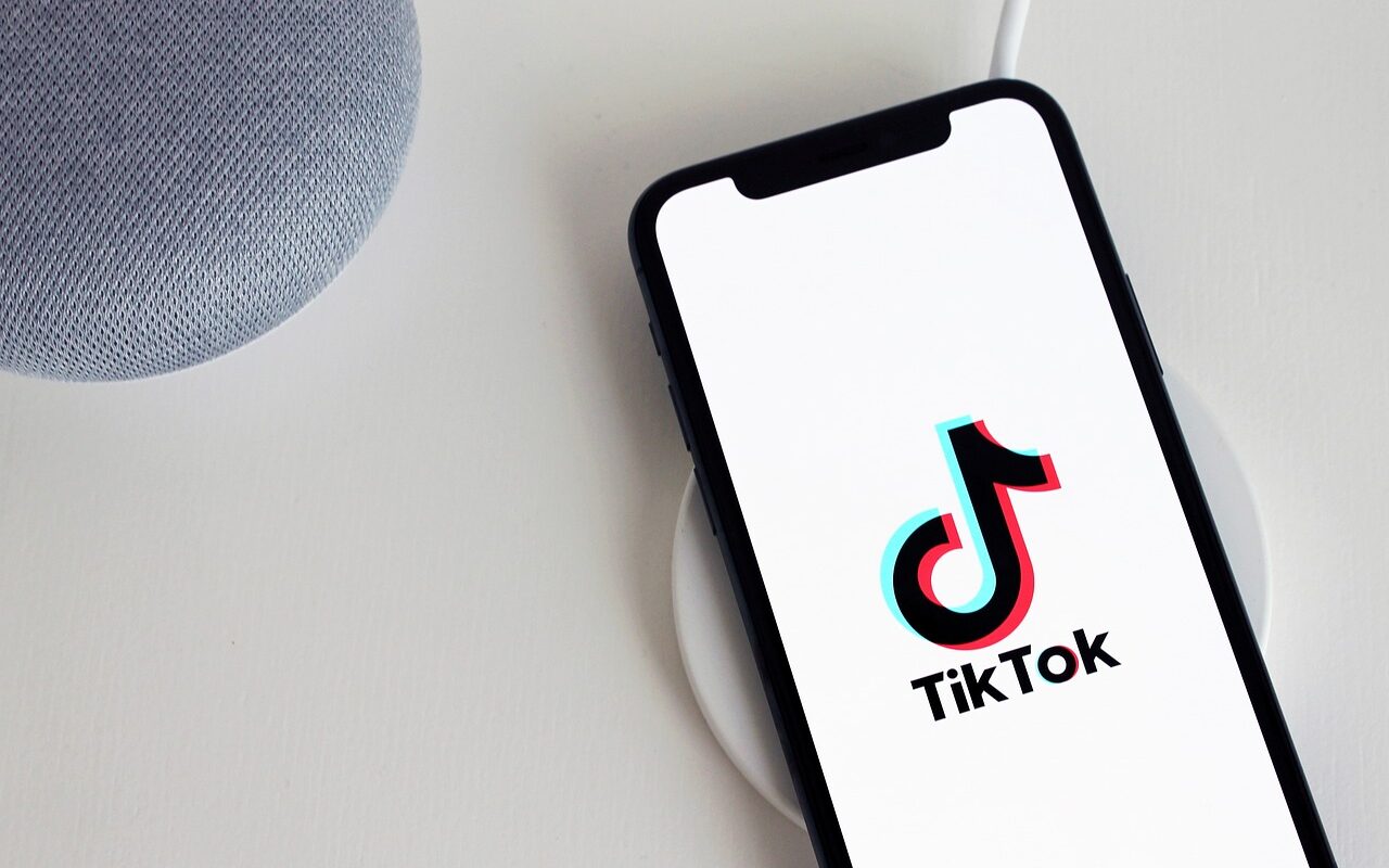 It is a picture of a mobile phone that is positioned on the left side and it shows TikTok logo